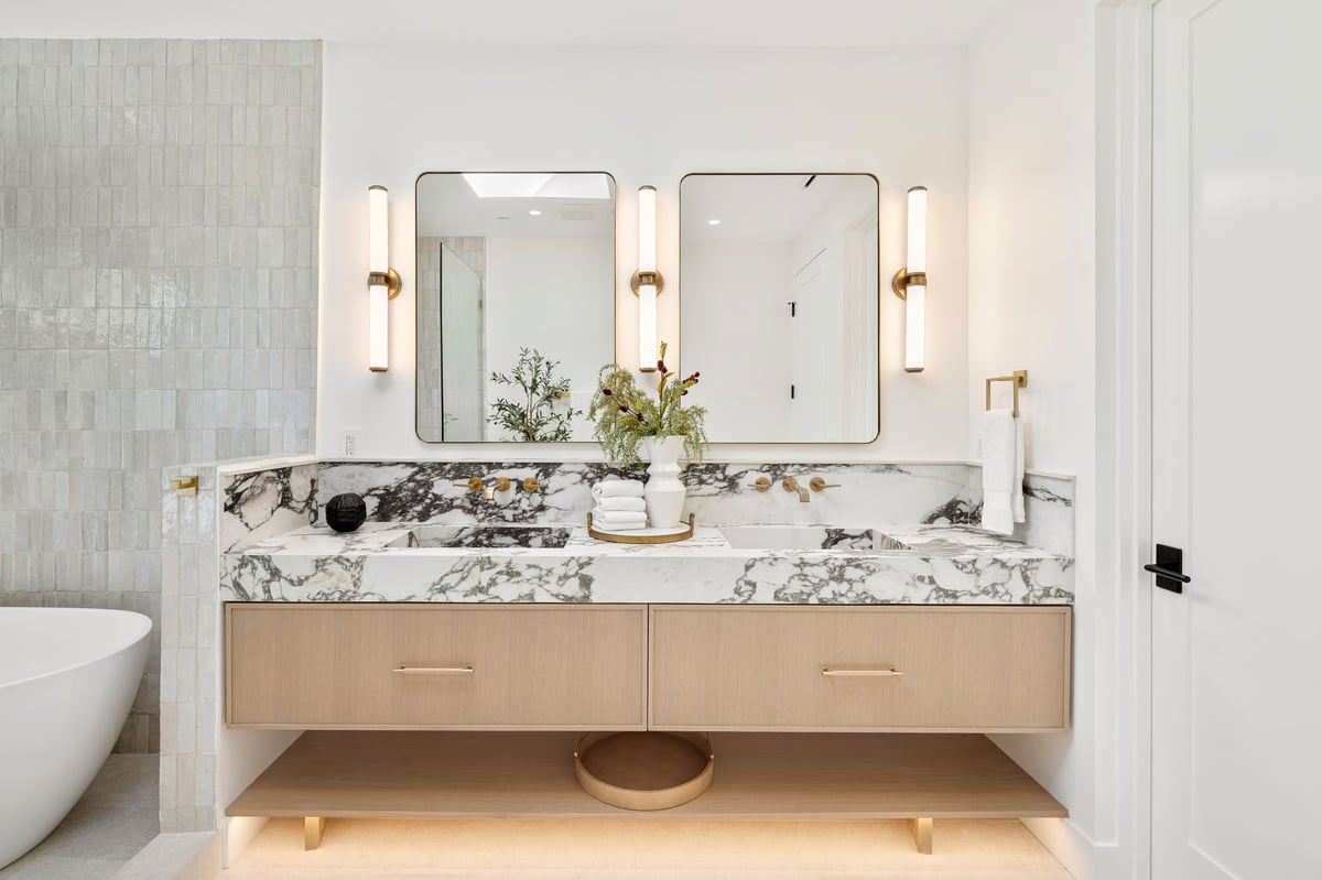 Luxury bathroom with marble double vanity countertop, dual mirrors, and elegant lighting